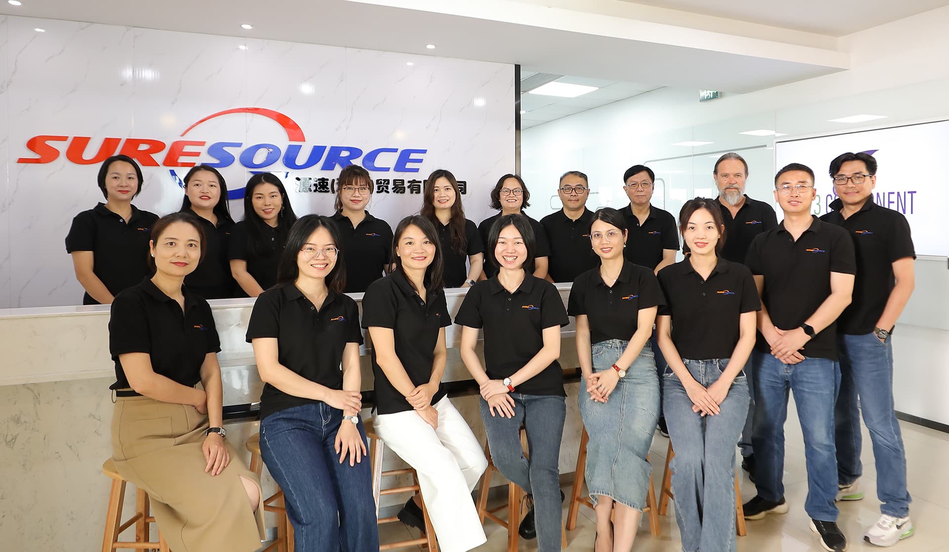 Group shot of Sure Source team in front of Sure Source logo in office lobby