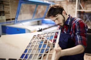 Professional engineer looking at plywood sheet with cut cells